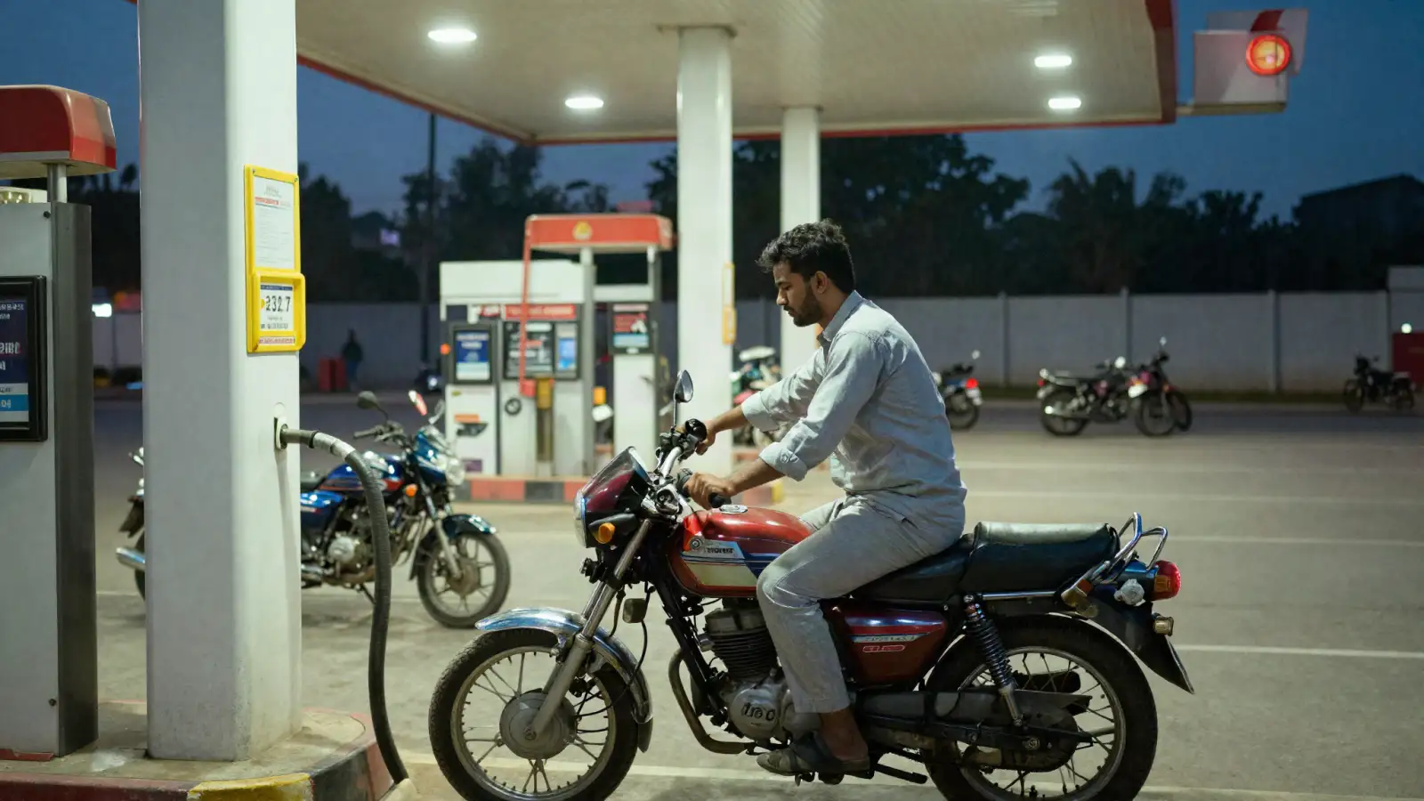 Young man refuelling his motorcycle at a petrol station in Lahore in the evening